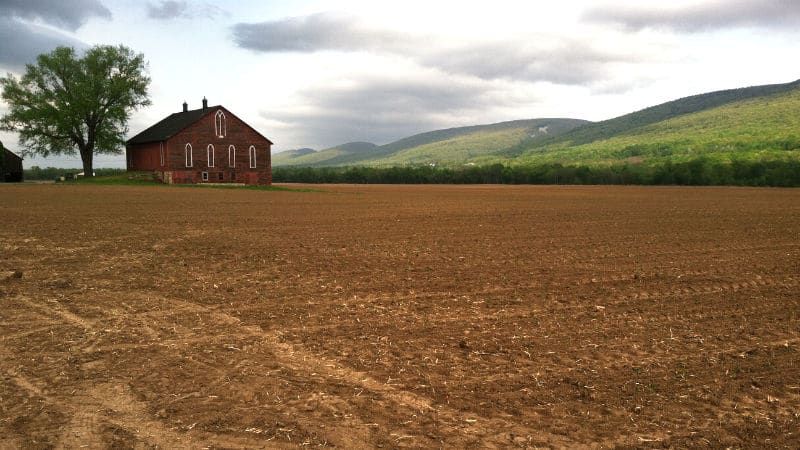 red-building-vast-plowed-field.jpeg